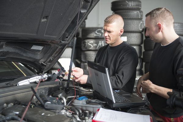 Zwei Männer mit Diagnosegeräten an der Motorhaube